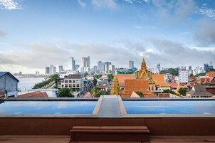 Una piscina en la azotea con vista al horizonte urbano y un templo.