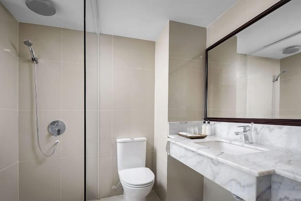 Un baño moderno con ducha, inodoro y lavamanos de mármol.
