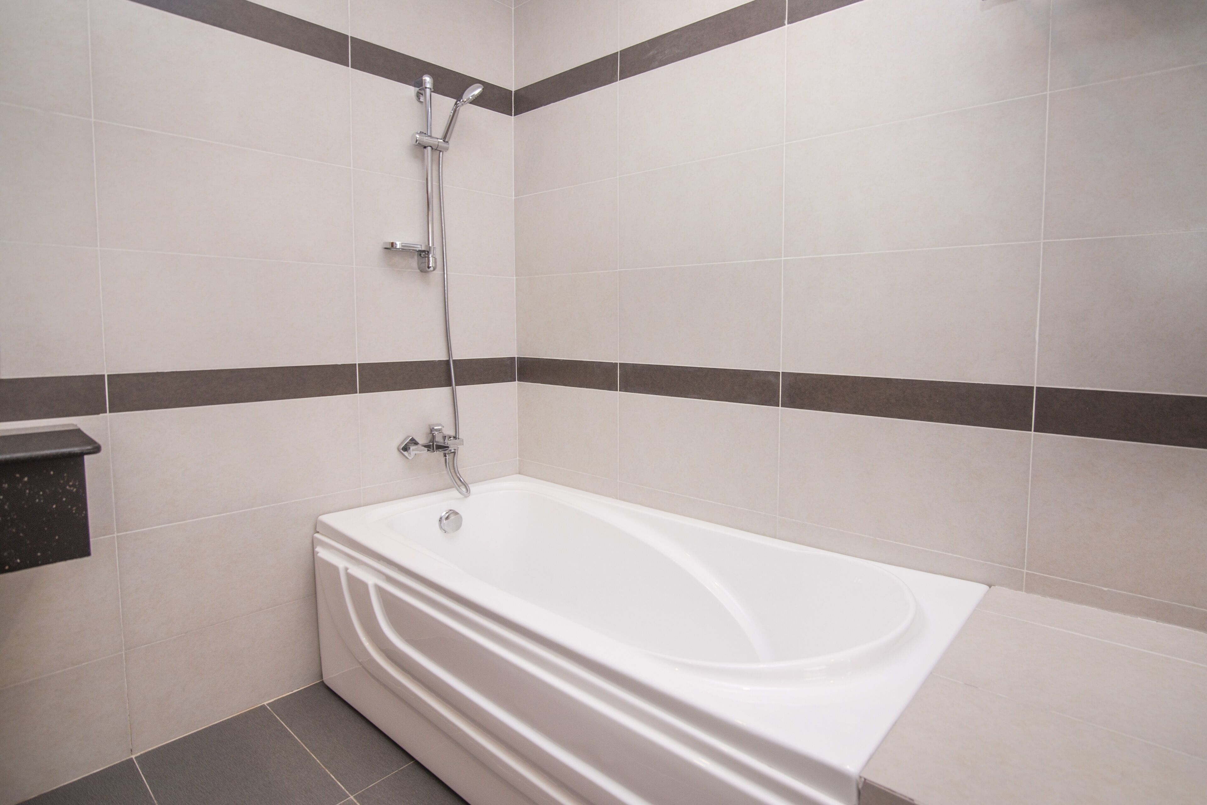 A bathroom with a white bathtub, a showerhead, and a toilet.