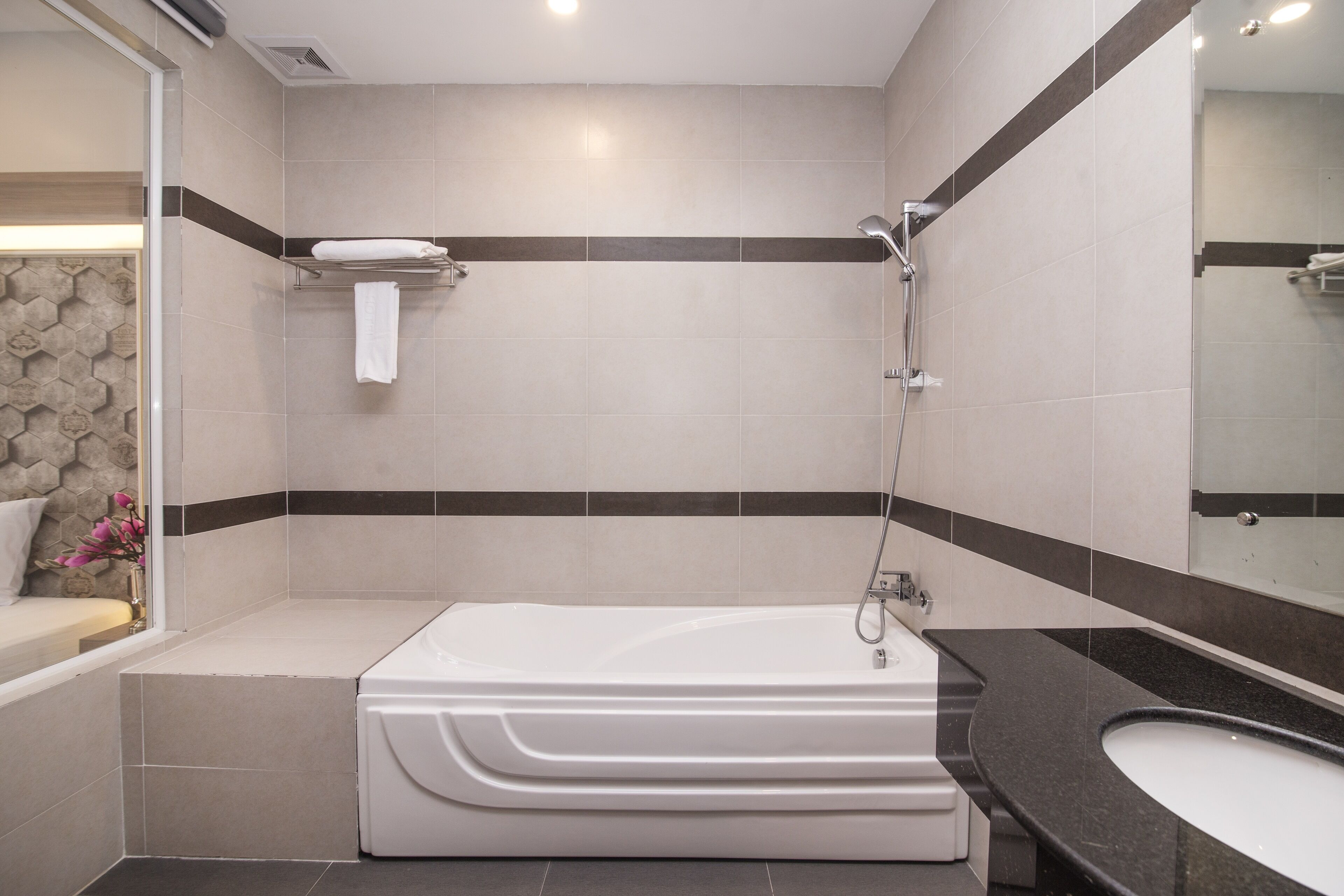 A modern bathroom with a bathtub, a large mirror, and a black countertop sink.