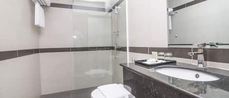 A modern bathroom with a glass-enclosed shower, a white toilet, and a black marble sink.