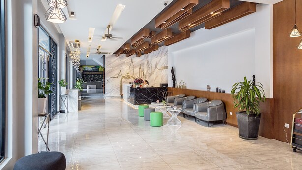 A modern lobby with a reception desk, seating area, and a marble wall with a cityscape mural. - New York Hotel (Phnom Penh)