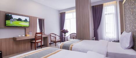 A hotel room with two beds, a desk, a TV, and a window with curtains.