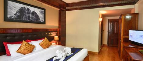A hotel room with a large bed, a television, and a framed picture on the wall.
