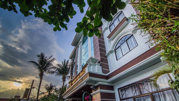 A multi-story building with a traditional architectural style, featuring a balcony with a decorative railing and a sign above it.