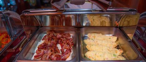 A buffet with various food items including bacon and scrambled eggs.