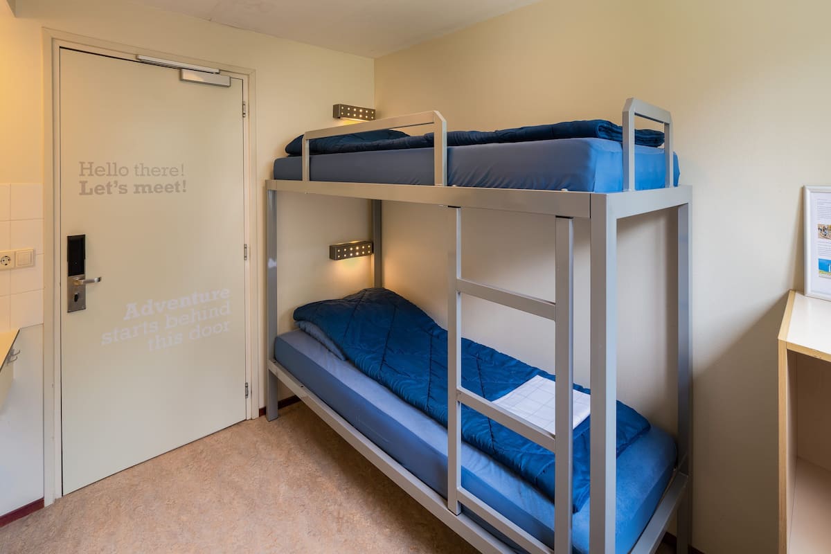 Une chambre avec des lits superposés, dont la porte porte un message motivant.