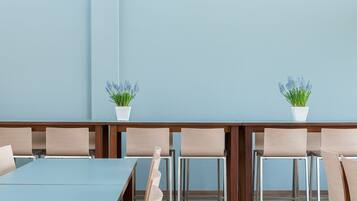 Une salle de conférence avec une longue table, de nombreuses chaises et deux plantes en pot posées sur la table.
