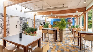 Un vaste espace intérieur doté de poutres en bois, d’un sol carrelé et de nombreuses tables et chaises.