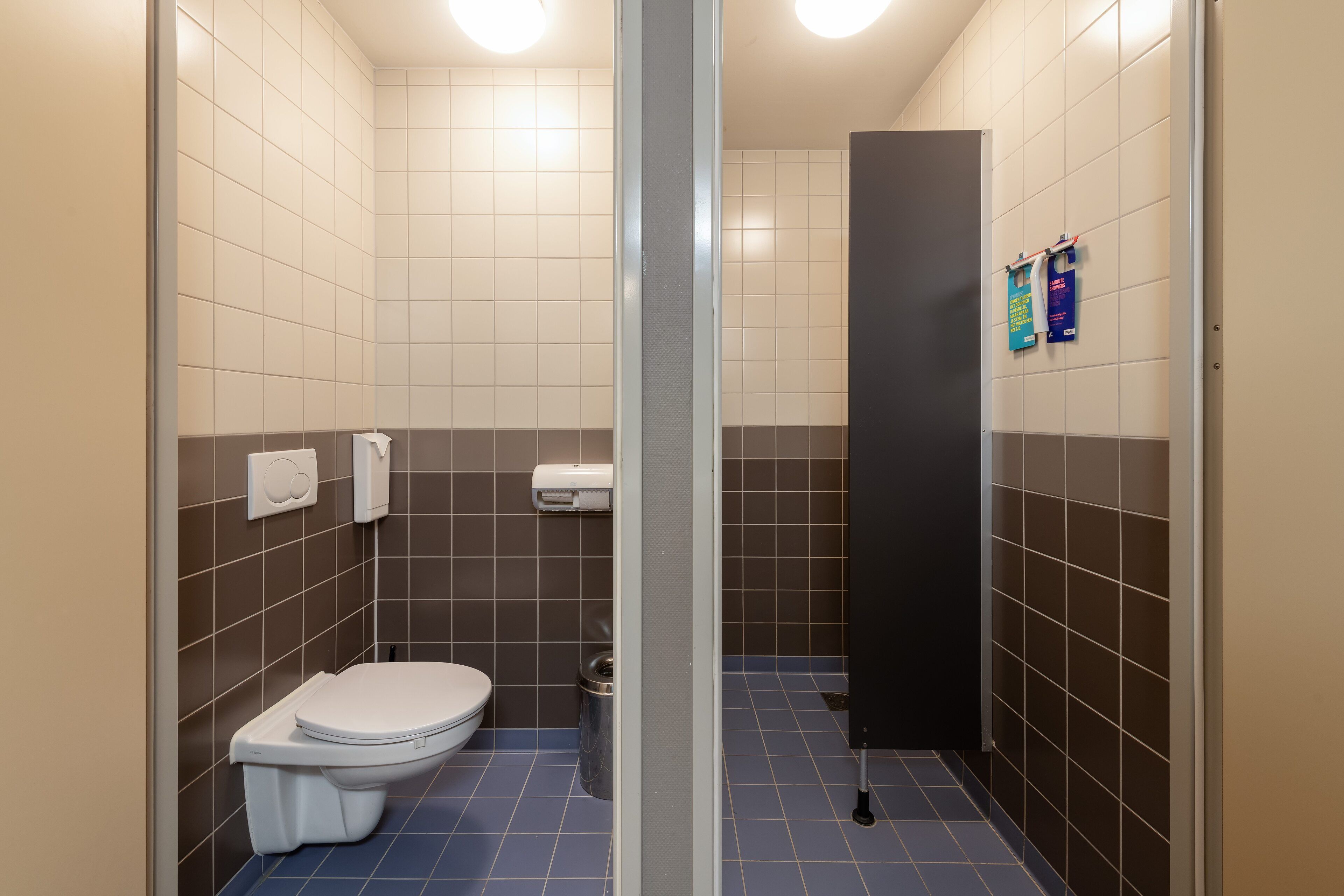 Een moderne badkamer met toilet, prullenbak en handdroger.