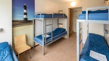 A bunk room with two bunk beds, a chair, and a wall-mounted light fixture.