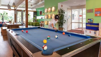 A pool table with balls, a person playing, and a green wall with various decorations.