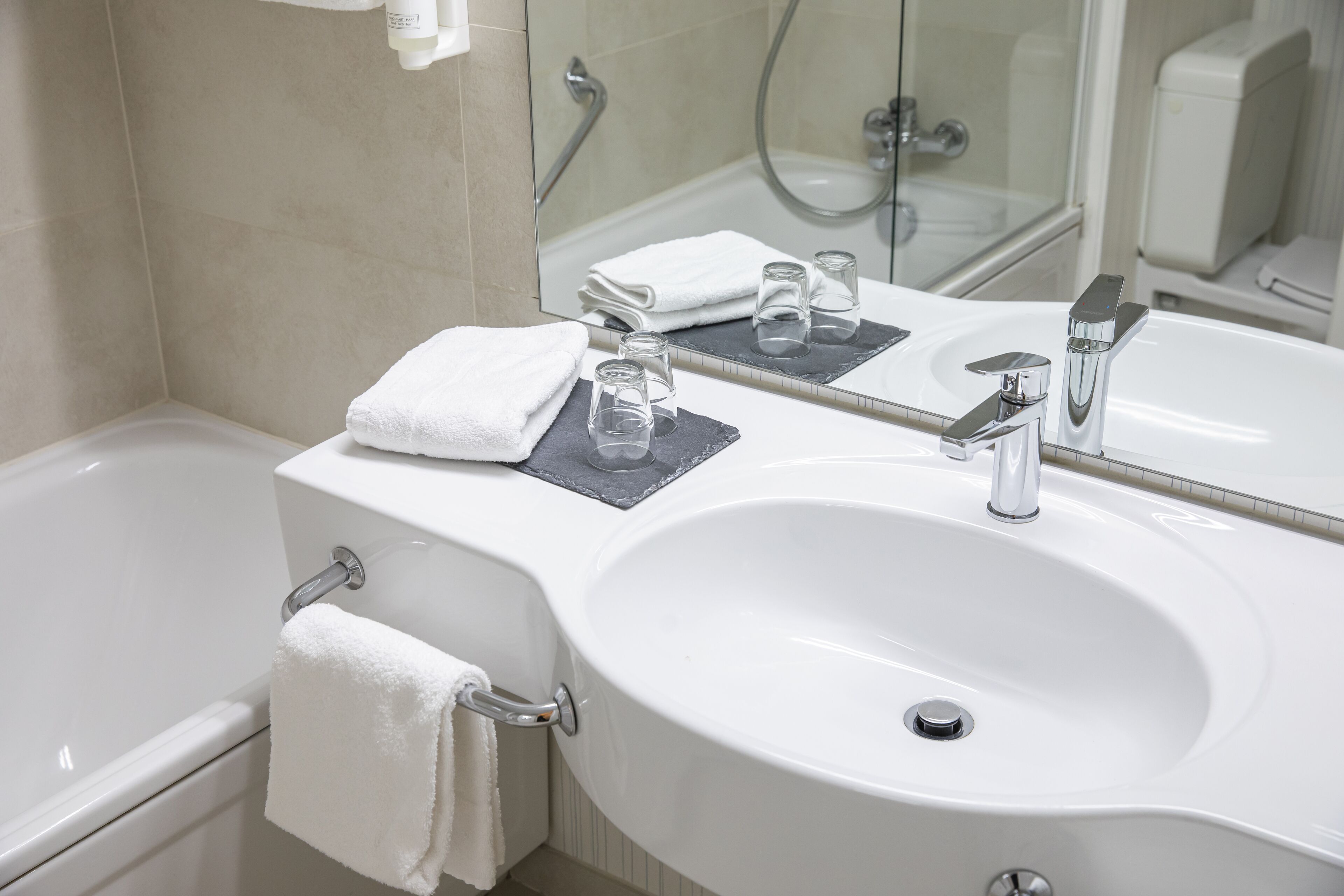Un baño moderno con lavamanos blanco, espejo y cabina de ducha de vidrio.