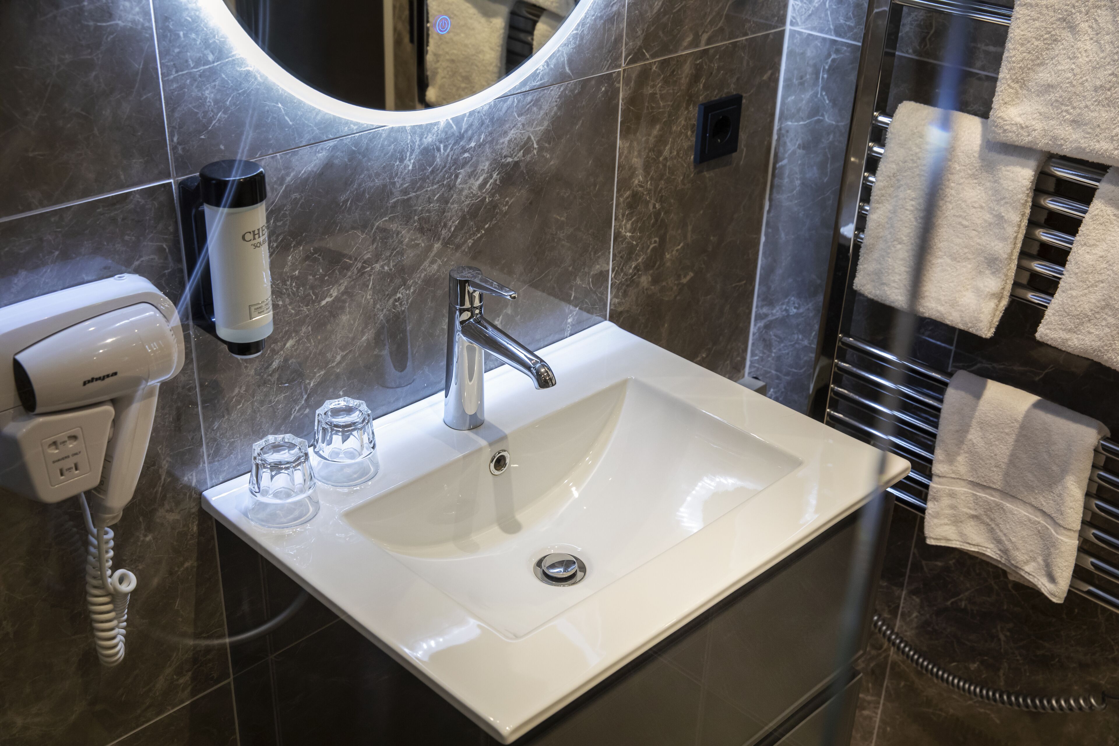 A bathroom with a white sink, a mirror, a towel rack, and a hand dryer.