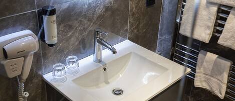 A bathroom with a white sink, a mirror, a towel rack, and a hand dryer.