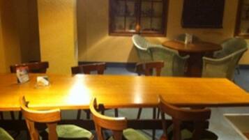 A dining area with a long wooden table, several chairs, and a window with blinds.