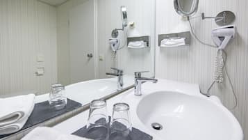 Une salle de bain moderne avec un grand lavabo, un miroir, un sèche-cheveux et un porte-serviettes.
