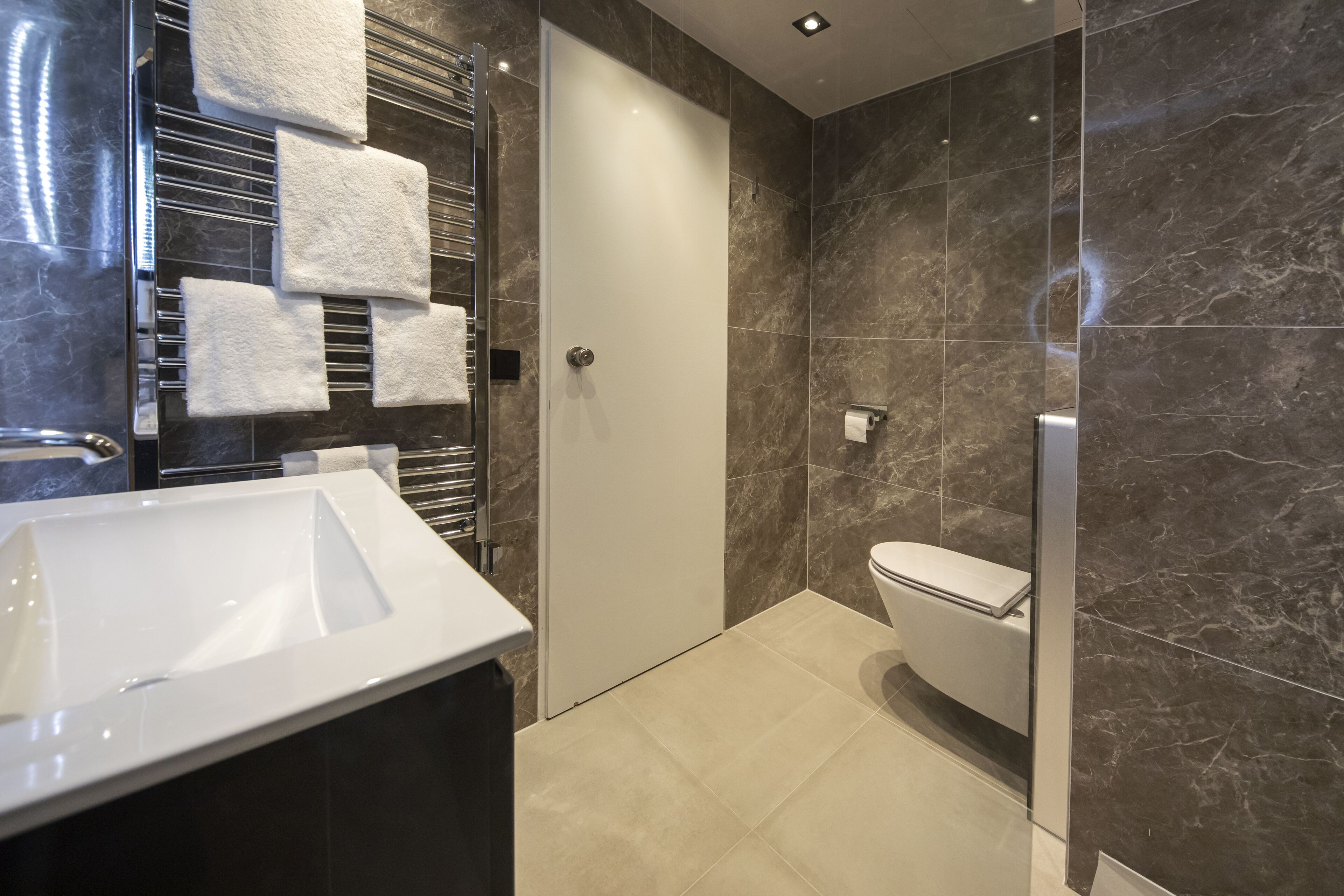 A modern bathroom with a white sink, a glass shower enclosure, and a toilet.