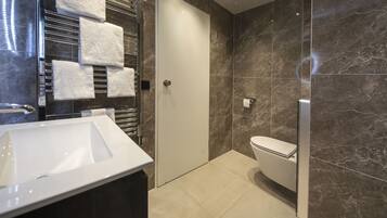 A modern bathroom with a white sink, a glass shower enclosure, and a toilet.