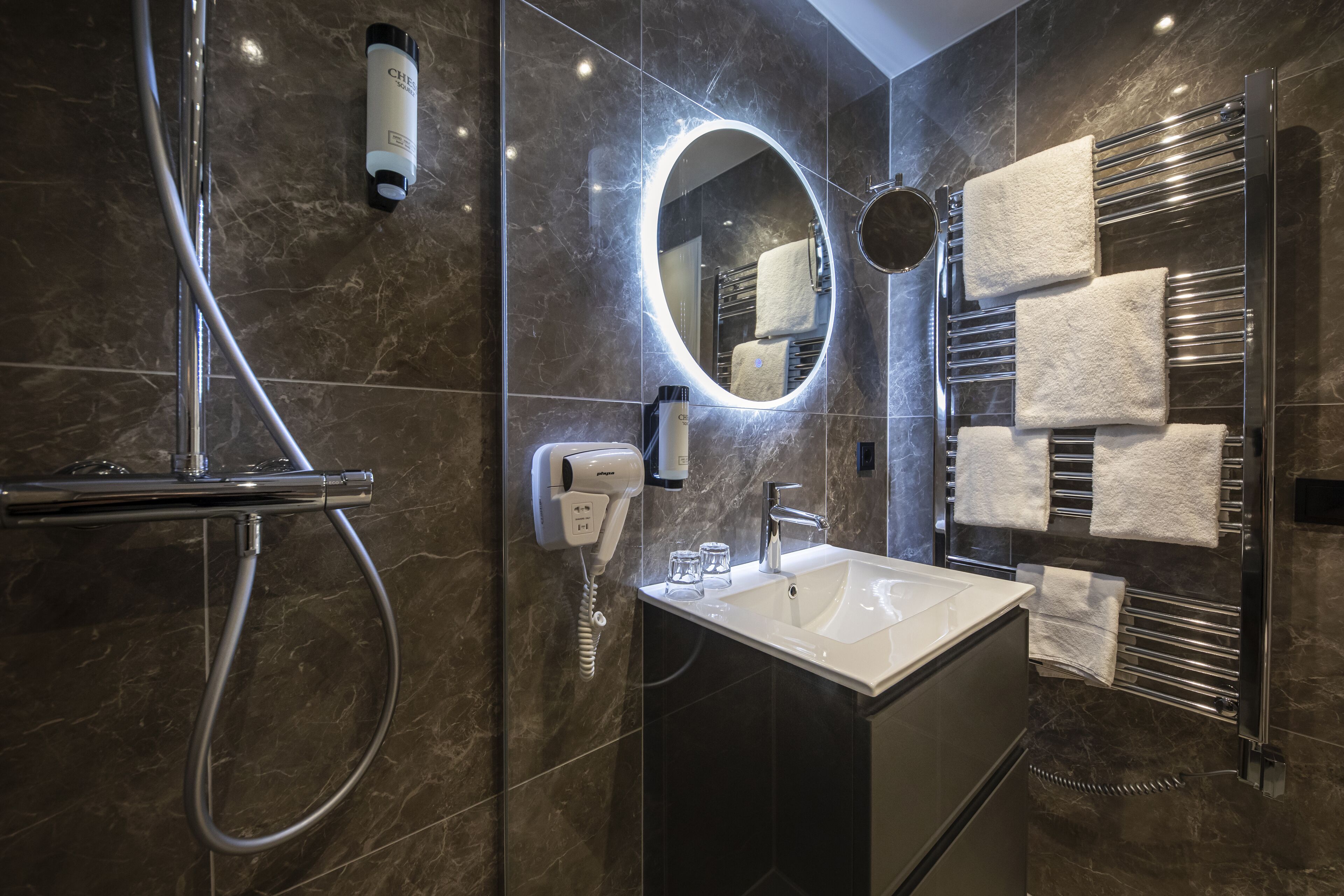 A modern bathroom with a shower, a sink, a mirror, and towel racks.