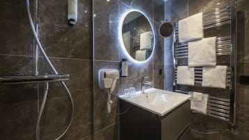 Un baño moderno con ducha, lavamanos, espejo y toalleros.