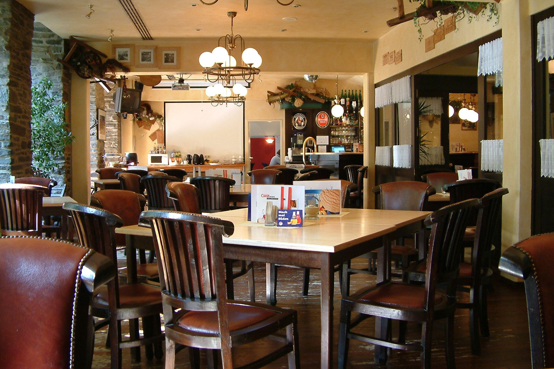 Un restaurant avec des tables et des chaises en bois, un coin bar et un lustre.