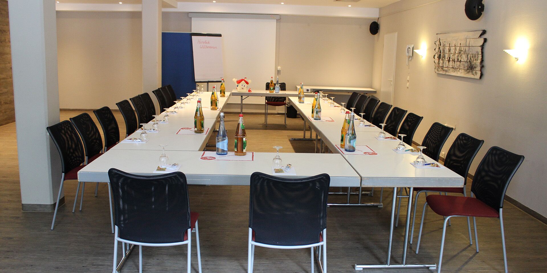 A conference room with a long table, chairs, and various items like bottles and glasses.