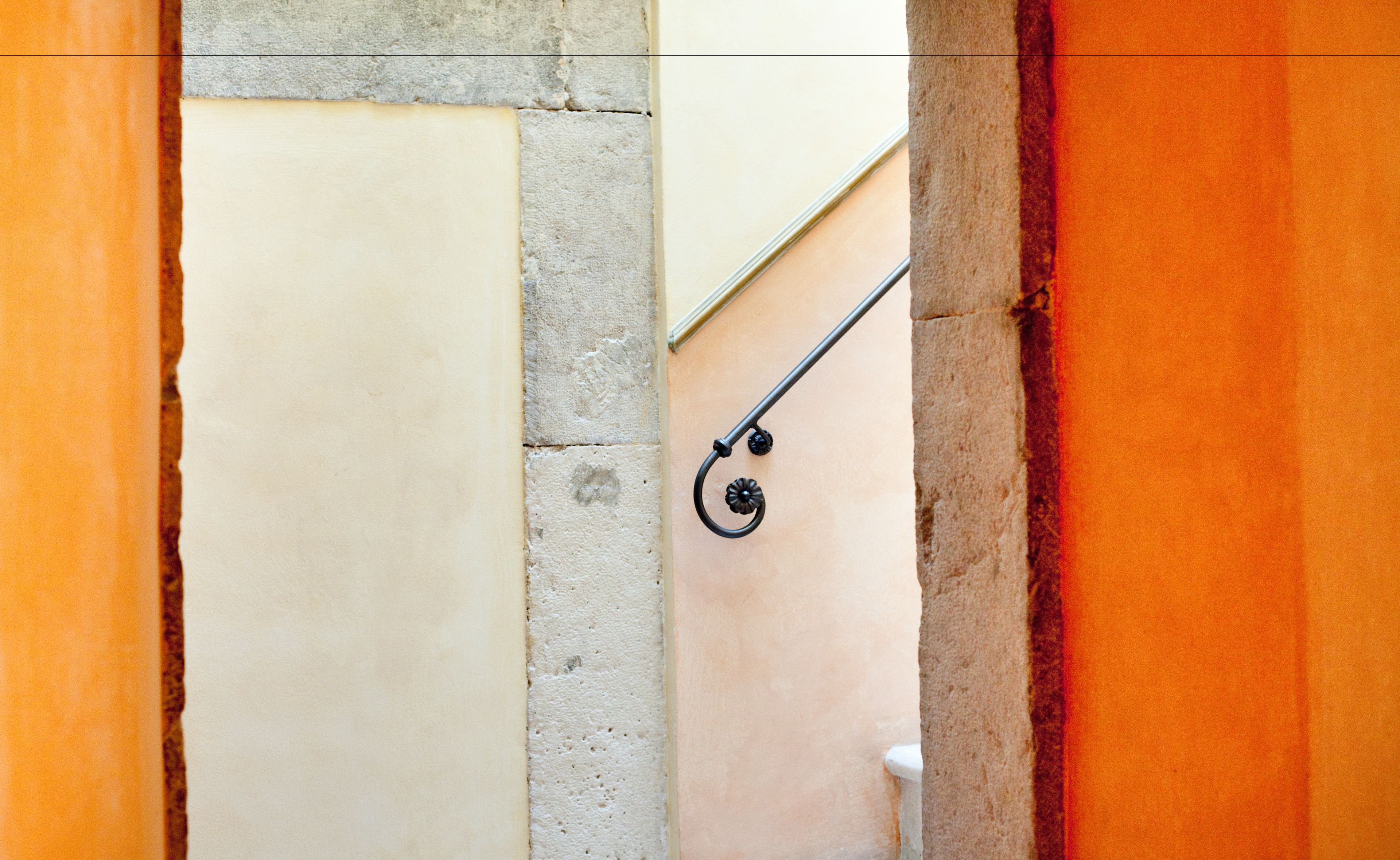 Un vano con barandilla de metal y una vista parcial de una pared color crema.