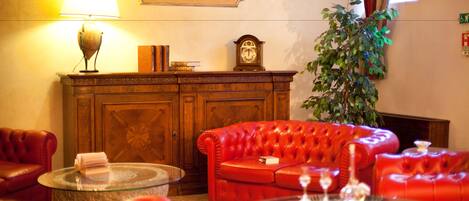A living room with a red sofa, a glass coffee table, a wooden cabinet, a lamp, and a clock.