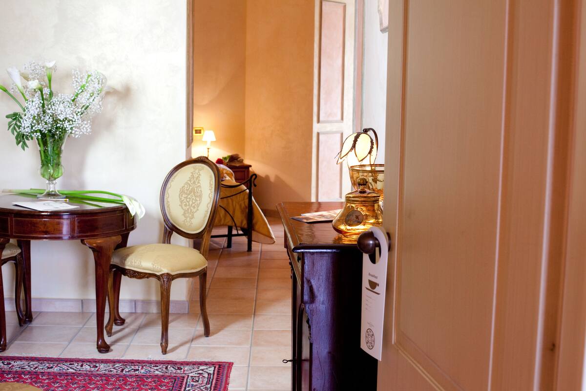 A dining area with a wooden table, a chair, a vase with flowers, and a lamp.