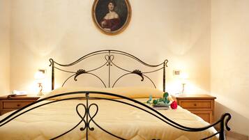 Un letto rifatto con cura, una testiera, due comodini con lampade e un ritratto incorniciato appeso al muro.