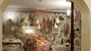 A rustic interior with stone walls, a hanging light fixture, and a small table with a bottle and a candle. - Hotel Villa Torre Antica (Atena Lucana)