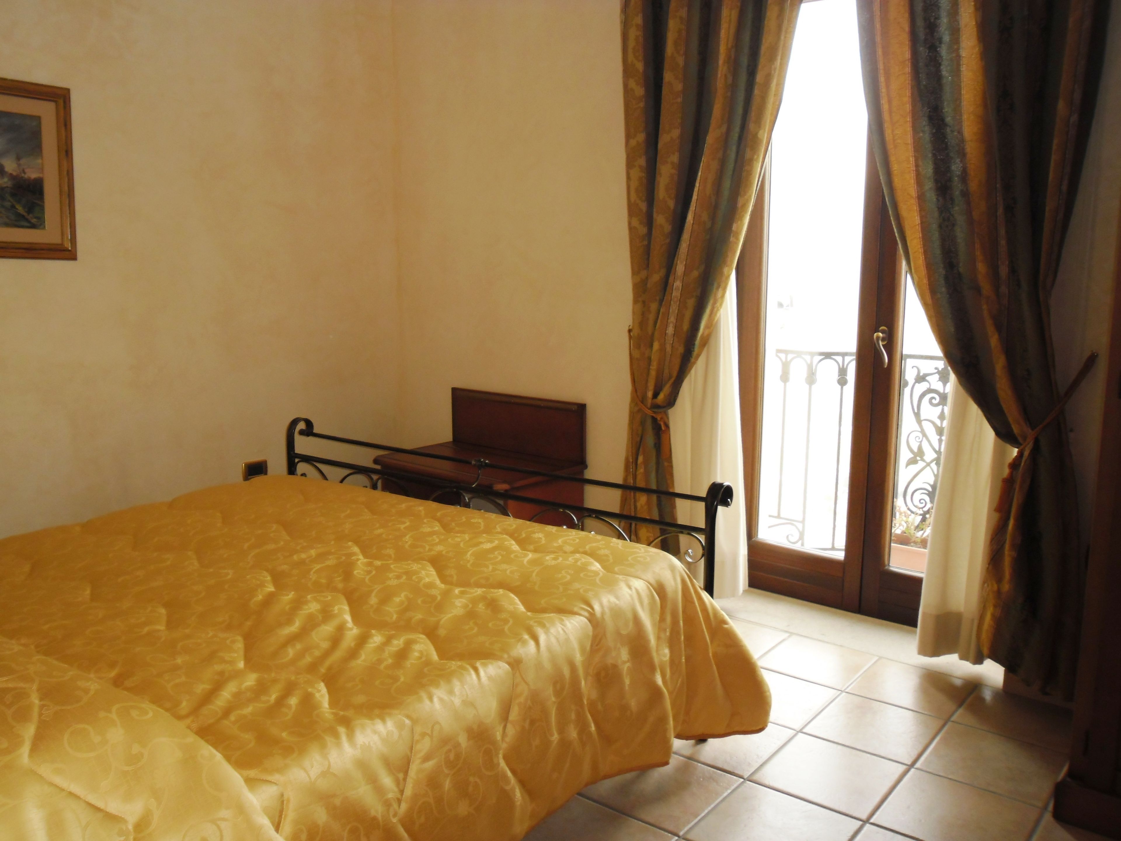 A bedroom with a bed, a wooden headboard, a small table, and a balcony with a railing.