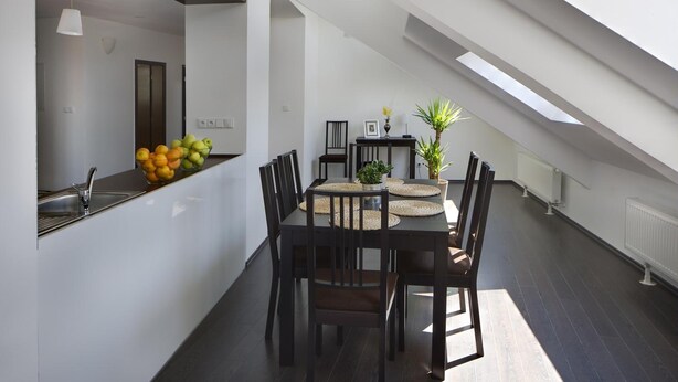 A modern kitchen with a dining area, featuring a dark wooden table and chairs, a fruit bowl, and a potted plant. - 1. Republic Hotel (Prague)