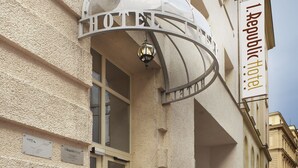 A hotel entrance with a marquee sign, a small kiosk, and potted plants. - 1. Republic Hotel (Prague)