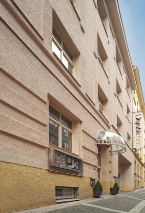 A hotel facade with a textured beige exterior, multiple windows, and a sign indicating it is a Republic Hotel.