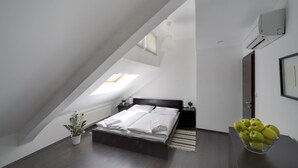 A bedroom with a skylight, a bed, a bedside table with a plant, and a bowl of fruit on a dresser. - 1. Republic Hotel (Prague)