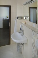 Uma casa de banho moderna com uma pia branca, um espelho e um porta-toalhas.