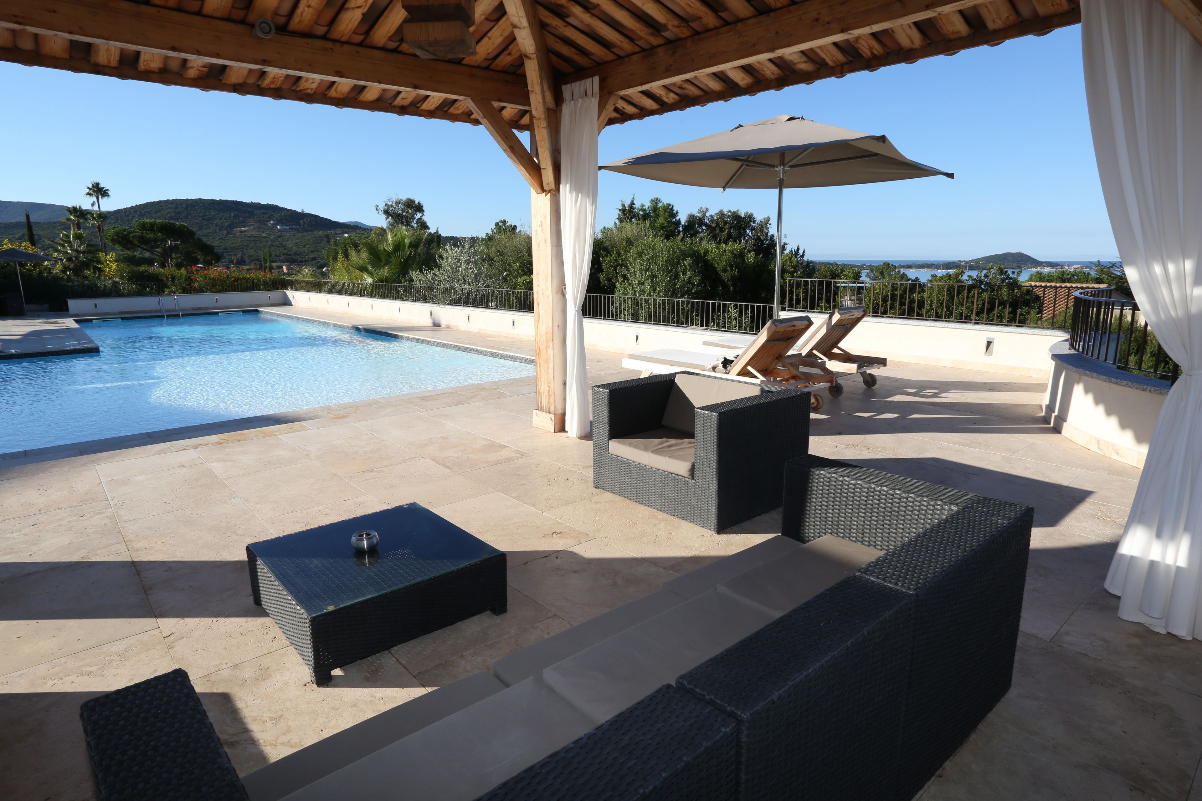 Ein Poolbereich mit Korbmöbeln, einem Tisch und einem Sonnenschirm.