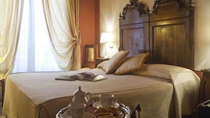 A neatly made bed with a tray of breakfast items, a bedside lamp, and a wooden headboard. - Relais San Lorenzo (Lucca)