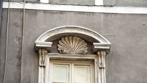 A building facade with a classical architectural style, featuring a symmetrical window with a decorative arch and a shell motif above it. - Relais San Lorenzo (Lucca)