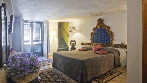 A bedroom with a bed, a large mirror, a staircase, and a potted plant. - Relais San Lorenzo (Lucca)