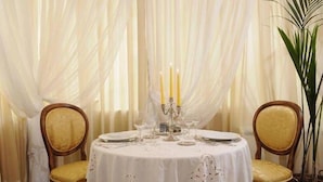 A round dining table with a white tablecloth, two chairs, and a candelabra with candles. - Relais San Lorenzo (Lucca)