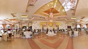 A spacious banquet hall with multiple round tables, elegant chandeliers, and a large floral mural on the wall. - Agriturismo Al Parco (Lecce)