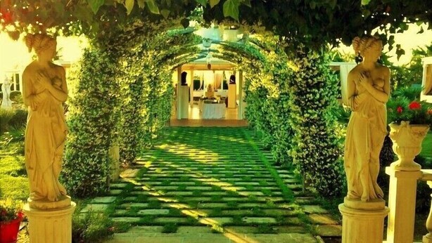 A garden pathway leading to a building under a vine-covered archway. - Agriturismo Al Parco (Lecce)