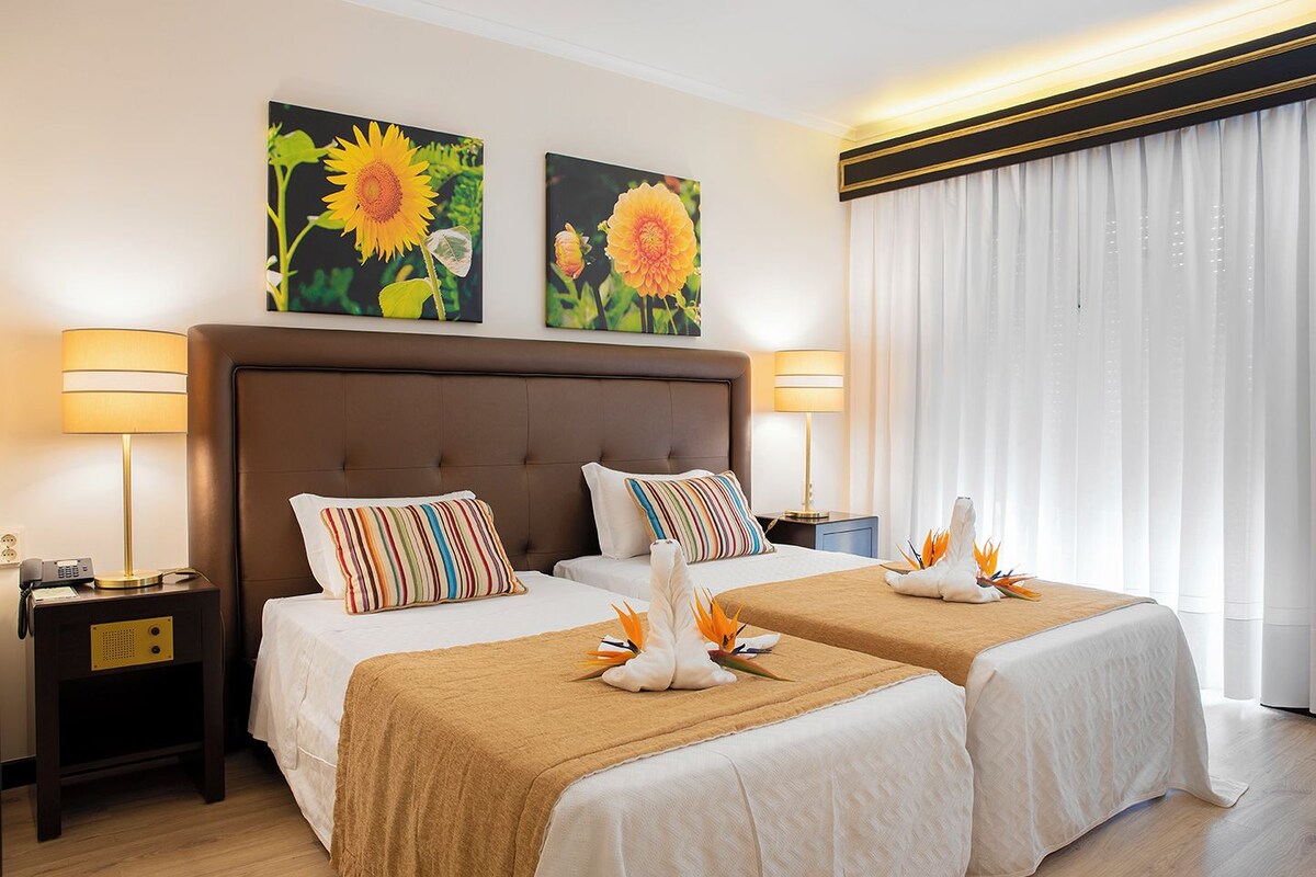 Une chambre d’hôtel avec deux lits, une grande tête de lit et des œuvres d’art accrochées au mur.