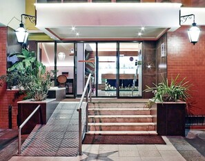 A hotel entrance with a glass door, a staircase, and potted plants. - Hotel Jardim (Aveiro)