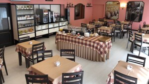 A dining area with tables covered in checkered tablecloths, a coffee station, and a wall-mounted refrigerator. - Hotel Jardim (Aveiro)