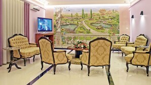 A spacious living room with a large TV, comfortable seating, and a scenic mural on the wall. - Hotel Jardim (Aveiro)
