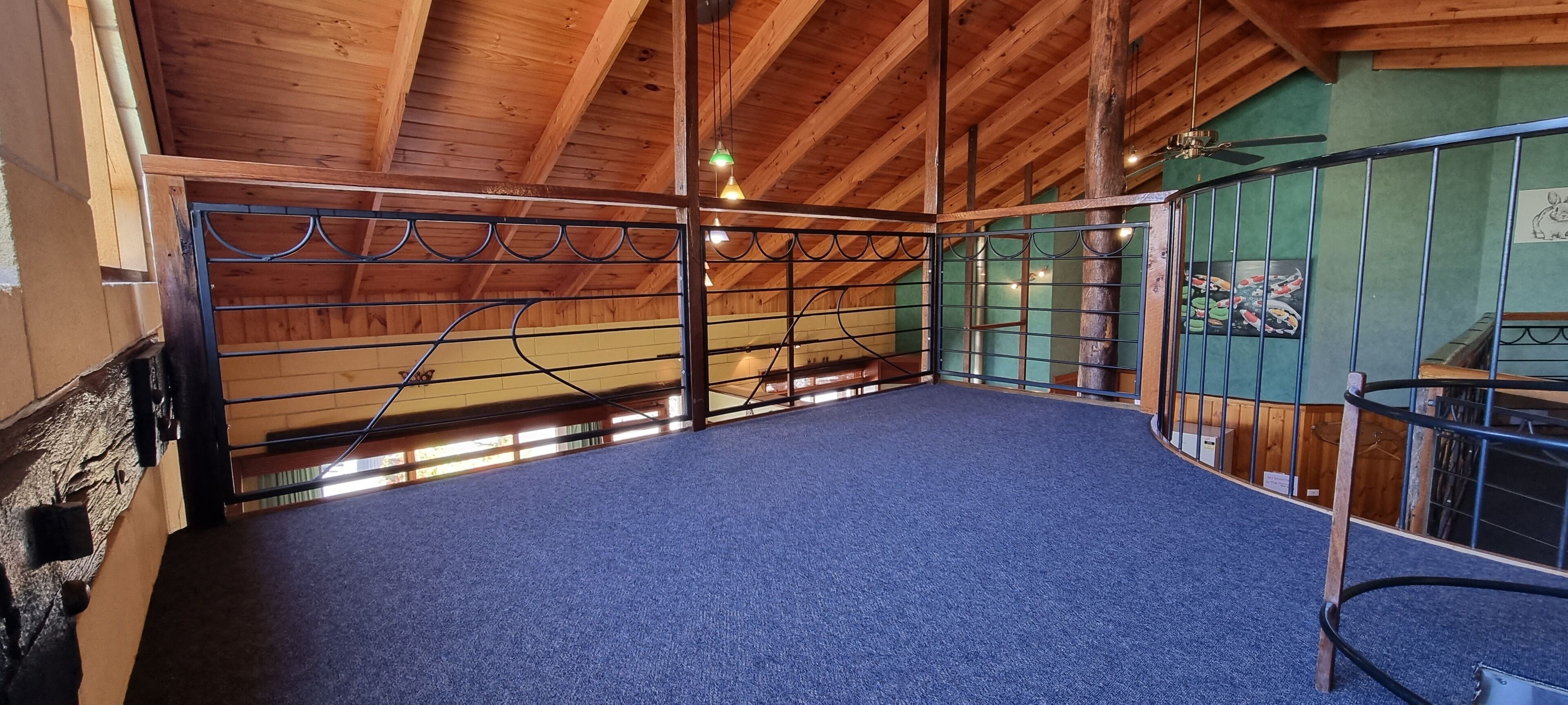 A stable with a blue carpet floor, wooden beams, and metal railings.